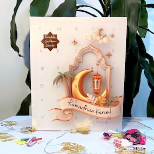 Pu&ograve; includere: Calendario del conto alla rovescia del Ramadan con una luna crescente dorata, una lanterna e decorazioni a stella. Il calendario presenta il testo "Ramadhan Karim!" su uno striscione. Sfondo chiaro con numeri.