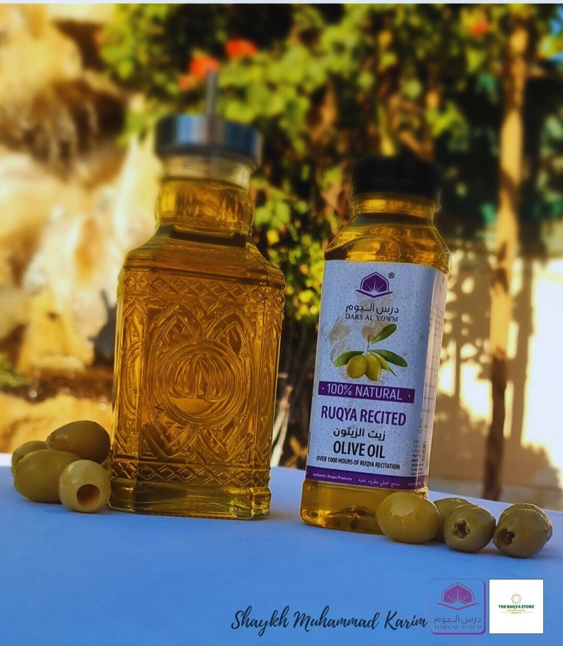 Puede incluir: Dos botellas de aceite de oliva, una en una botella de vidrio transparente con un dise&ntilde;o decorativo y la otra en una botella de pl&aacute;stico transparente con una etiqueta que dice "Dars Al Yowm 100% Natural Ruqya Recitada Aceite de Oliva M&aacute;s de 1000 horas de recitaci&oacute;n de Ruqya". Las botellas est&aacute;n sobre una superficie blanca con aceitunas verdes.