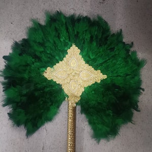 May include: A green feather fan with a gold handle and a gold and white beaded design in the center.  The fan is closed.