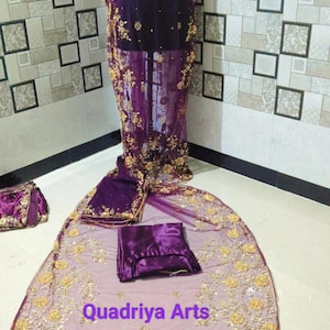 Peut inclure: Une robe de soirée violette avec des broderies dorées et un châle assorti. La robe est présentée sur un mannequin, avec une superposition transparente et des motifs floraux complexes. Le texte "Quadriya Arts" est visible sur le châle.