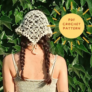 May include: A white crochet sun hat with a delicate floral pattern. The hat is worn by a person with long brown hair styled in braids. The image includes the text "PDF CROCHET PATTERN".