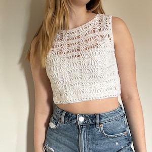 K&ouml;nnte beinhalten: Wei&szlig;es H&auml;kel-Crop-Top mit einem zarten Lochmuster. Das Top ist &auml;rmellos und hat einen runden Ausschnitt.