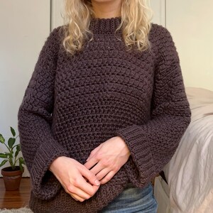 May include: A brown crocheted sweater with a high neck and long sleeves.