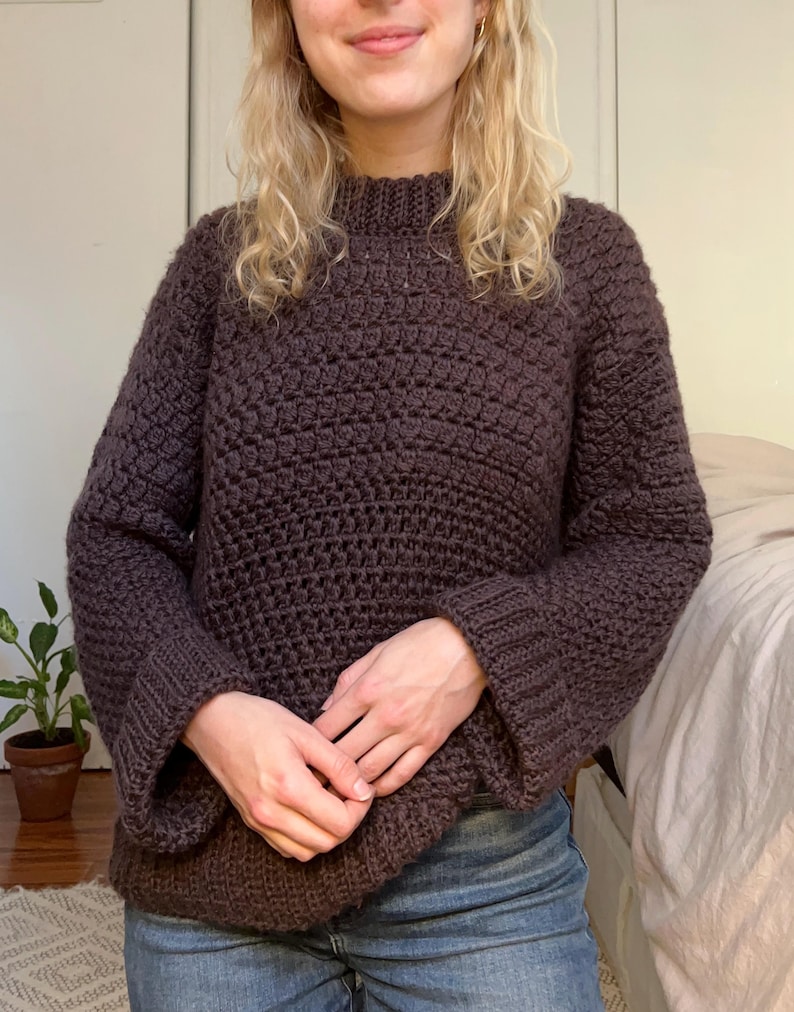 May include: A brown crocheted sweater with a high neck and long sleeves.