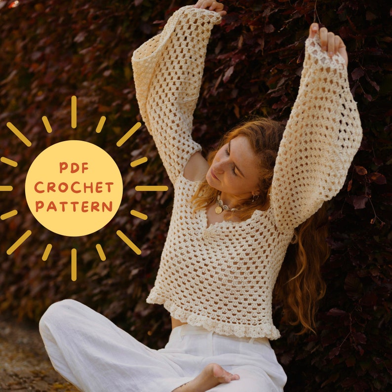 May include: A woman wearing a white crochet top with bell sleeves. The top has a crochet stitch pattern and a v-neck. The woman is sitting with her arms raised above her head. The image includes the text "PDF CROCHET PATTERN".