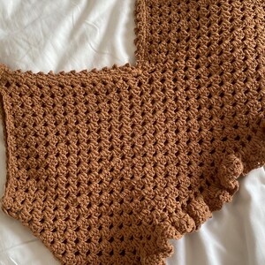 May include: A brown crocheted top with a scalloped edge.