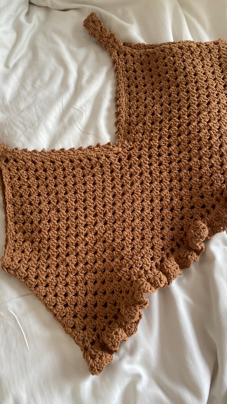 May include: A brown crocheted top with a scalloped edge.