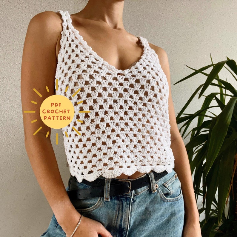 Op de afbeelding: Wit gebreid tanktop met een gegolfde zoom. Het topje is gemaakt met een eenvoudig steekpatroon en heeft een ontspannen pasvorm. De afbeelding bevat de tekst "PDF CROCHET PATTERN".