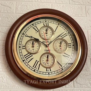 Puede incluir: Un reloj de pared redondo con marco de madera y una cara dorada con marcas de números romanos. El reloj tiene cuatro relojes más pequeños en el interior, cada uno con una zona horaria diferente. La cara del reloj dice "World Time".