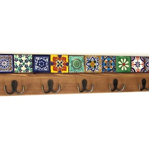 Könnte beinhalten: Ein Wandgarderobe aus Holz mit dekorativen Keramikfliesen und acht Metallhaken. Die Fliesen zeigen farbenfrohe Muster in Blau, Gelb, Grün und Orange. Die Garderobe ist etwa 91 cm lang.