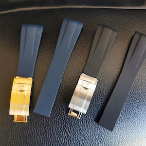 Puede incluir: Cuatro correas de reloj en azul marino y negro, con cierres dorados y plateados. Las correas están hechas de un material flexible y están diseñadas para sujetarse a una esfera de reloj. Los cierres son rectangulares.