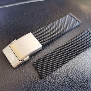 May include: A black rubber watch strap with a silver buckle. The strap has a textured pattern and is designed for a watch with a 22mm lug width.