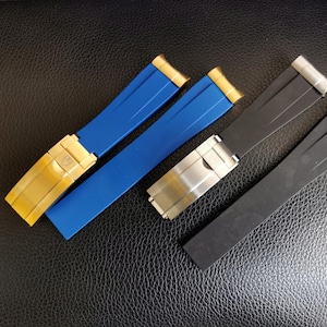 May include: Three watch straps, one blue, one black, and one blue with a gold buckle. The straps are made of rubber and have a sporty look.