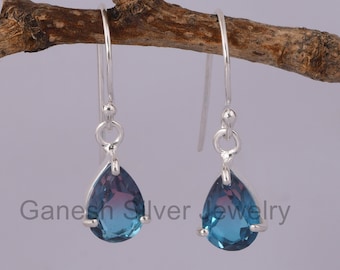 May include: A pair of sterling silver teardrop earrings with blue gemstone drops. The earrings have a simple design and are perfect for everyday wear.