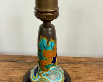 May include: A ceramic wall sconce with a blue, green, orange, and gold floral design. The sconce has a white porcelain socket and a brass fixture.