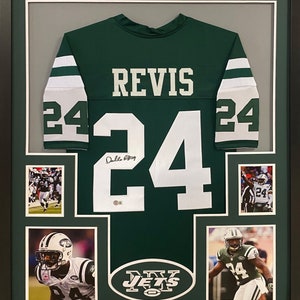 May include: A framed green and white New York Jets jersey with the number 24 and the name "Revis" on the back. The jersey is signed by "Revis" and includes three smaller photos of the player in action.