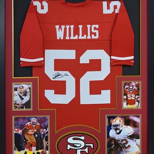 May include: Framed red football jersey with the name "WILLIS" and the number "52" in white. Includes four smaller photos and a team logo. The jersey is signed. The frame is black with a red and gold border.