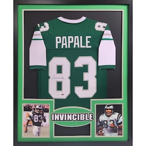 May include: A framed green football jersey with the name "PAPALE" and the number "83" on the back. The jersey is signed by the player. The frame includes two smaller photos of the player in action. The text "INVINCIBLE" is printed on the frame.