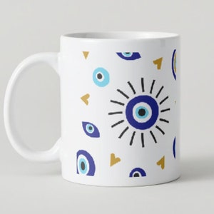 Puede incluir: Taza de cerámica blanca con un patrón de ojos malos azules y blancos y corazones dorados.