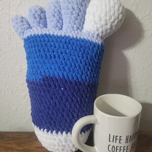 May include: A blue, white, and light blue crocheted hand-shaped pillow with a white mug that says "Life Happens, Coffee Helps".