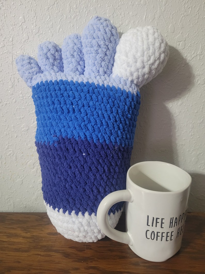 May include: A blue, white, and light blue crocheted hand-shaped pillow with a white mug that says "Life Happens, Coffee Helps".