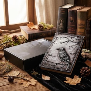 Puede incluir: Un libro decorativo con un diseño de cuervo en la portada, ambientado con otros libros antiguos y elementos naturales. El cuervo está posado en una rama, con una luna de fondo. El libro está abierto, mostrando sus páginas.