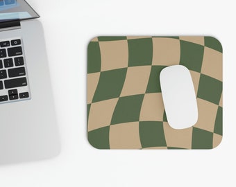 Peut inclure: Un tapis de souris rectangulaire présentant un motif en damier ondulé et déformé dans des tons alternés de vert forêt et de beige. Une souris d'ordinateur blanche et lisse repose sur le côté droit du tapis, à côté d'un ordinateur portable argenté.