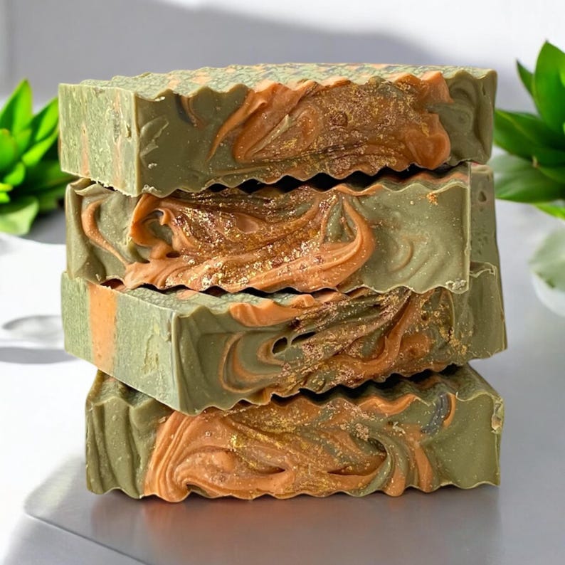 May include: Four bars of handmade soap stacked on top of each other. The soap is green and orange with gold glitter.