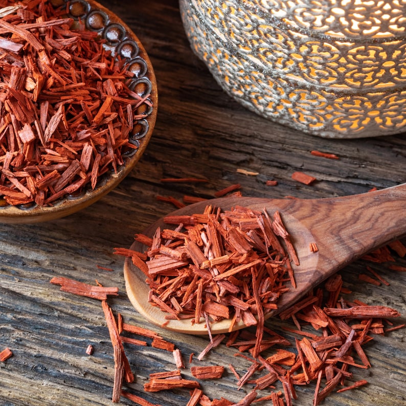 May include: Red sandalwood chips in a wooden bowl and spoon. The chips are a deep red color and have a fragrant aroma.