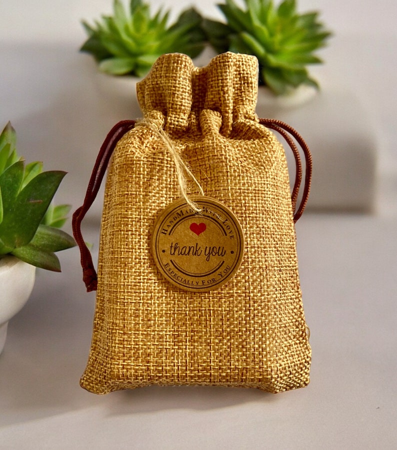 May include: A small burlap bag with a brown drawstring and a round brown tag that says "Handmade with Love, thank you, Especially for you". The tag has a red heart in the center.