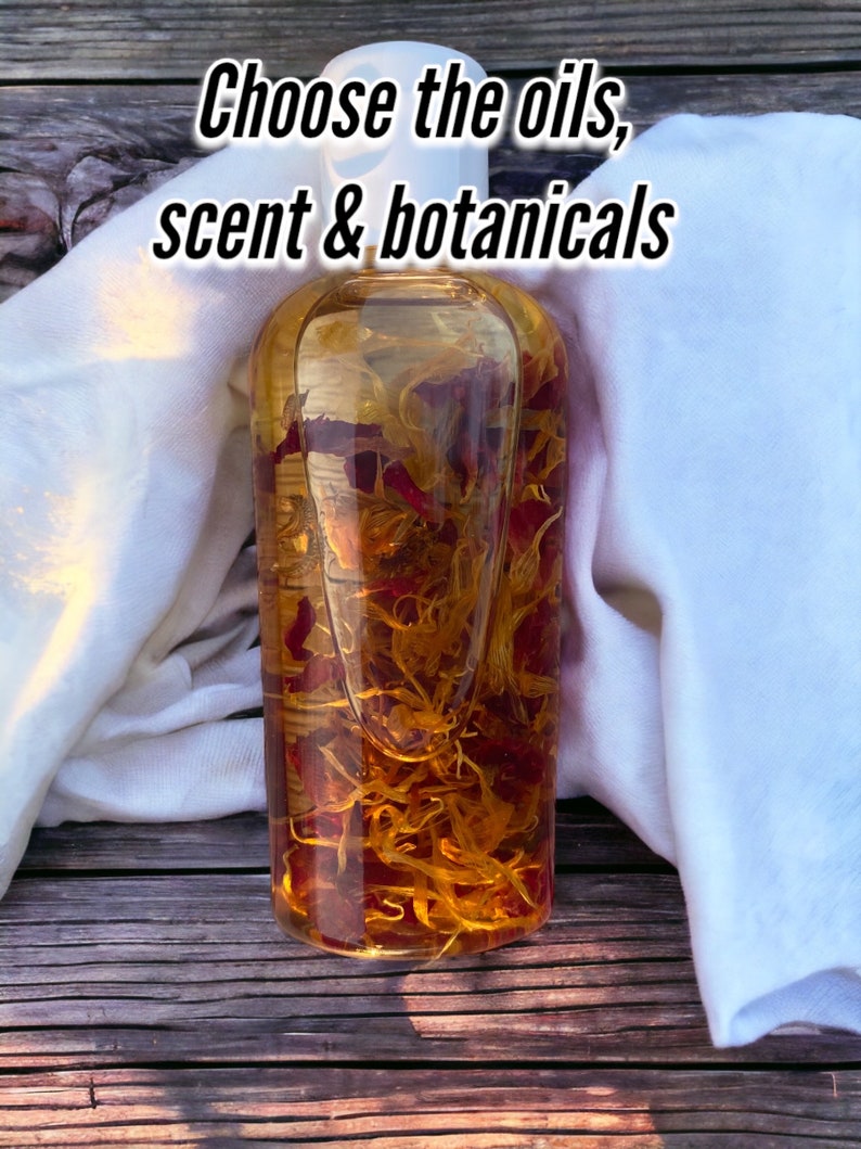 May include: A clear glass bottle filled with a golden liquid and red and yellow botanicals. The bottle is sitting on a wooden surface with a white cloth draped over it. The text "Choose the oils, scent & botanicals" is written in black text at the top of the image.