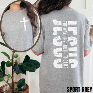 May include: A gray t-shirt with a white cross on the front and the words "Jesus The Way The Truth The Life" on the back. The shirt is labeled "Sport Grey".