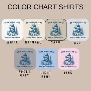 May include: Color chart for shirts with a bear graphic. The bear is sitting on a tree stump, holding a mug, and the text reads "IT IS WHAT IT IS AND IT'S NOT GREAT." The shirts come in white, natural, sand, ash, sport grey, light blue, and pink.