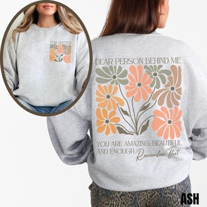Puede incluir: Sudadera gris con un dise&ntilde;o floral en la espalda y el texto "DEAR PERSON BEHIND ME YOU ARE AMAZING, BEAUTIFUL AND ENOUGH, Remember That". La parte delantera de la sudadera tiene el texto "YOU MATTER" con un peque&ntilde;o dise&ntilde;o floral.