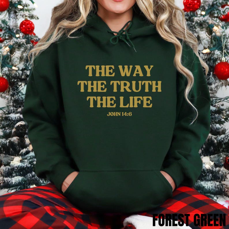 May include: Forest green hoodie with the text "THE WAY THE TRUTH THE LIFE JOHN 14:6" in gold lettering. The hoodie has a drawstring hood and a front pocket. The bottom of the hoodie has the text "FOREST GREEN".