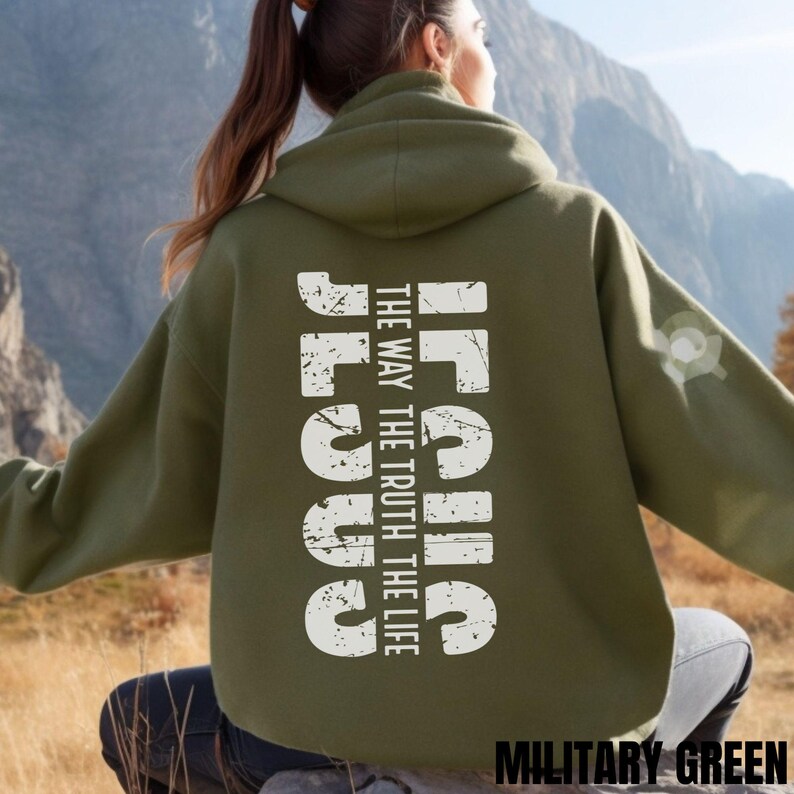 May include: A green hooded sweatshirt with the words "Jesus" in white, with the phrase "The Way The Truth The Life" underneath. The sweatshirt is shown on a model in front of a mountain background. The text "Military Green" is shown at the bottom of the image.