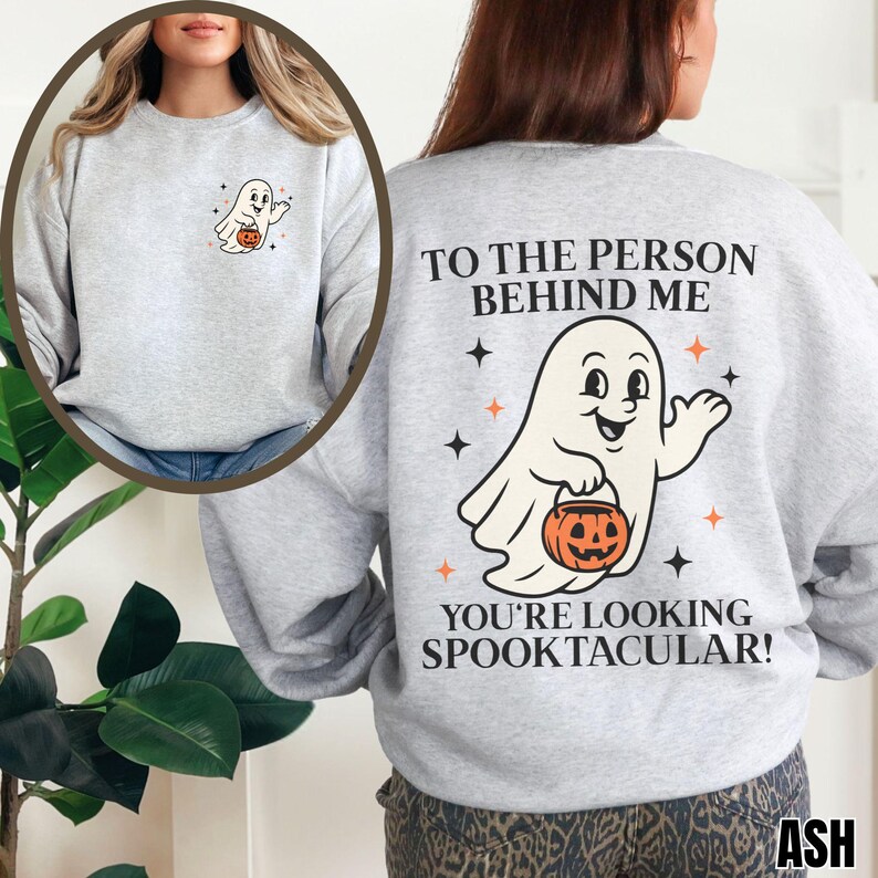 Puede incluir: Una sudadera gris claro de cuello redondo con un peque&ntilde;o gr&aacute;fico de fantasma en el pecho izquierdo y un gran estampado en la espalda que dice TO THE PERSON BEHIND ME YOU'RE LOOKING SPOOKTACULAR! con una ilustraci&oacute;n central de un fantasma con calabaza.