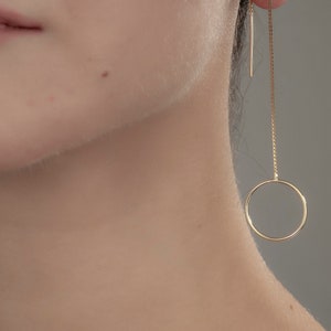 May include: Gold circle dangle earrings with a thin chain and a small circle pendant.