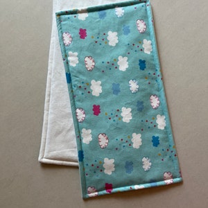 May include: Two fabric placemats, one white and one blue with a white cloud and pink star pattern.