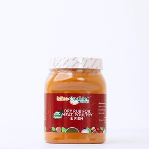 May include: A jar of Miss Cookie's Spices dry rub for meat, poultry, and fish. The jar has a red label with white text and a white lid. The spice blend is a light orange colour. The label also says "100% Natural".