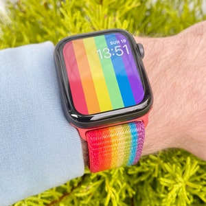 May include: A rainbow-coloured Apple Watch band with a black Apple Watch face displaying the time "13:51" and the date "SUN 19".