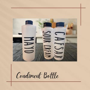 May include: Three white condiment bottles with black lids and labels. The labels read "Mayo", "Sour Cream", and "Caesar".