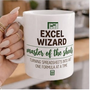 Peut inclure: Mug en céramique blanche avec l'inscription "EXCEL WIZARD master of the sheets" en marron et vert. La tasse présente également une icône de feuille de calcul et la phrase "TURNING SPREADSHEETS INTO ART ONE FORMULA AT A TIME."
