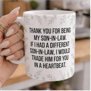 Peut inclure: Mug en céramique blanche avec texte noir : "THANK YOU FOR BEING MY SON-IN-LAW. IF I HAD A DIFFERENT SON-IN-LAW, I WOULD TRADE HIM FOR YOU IN A HEARTBEAT." Décor floral.