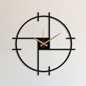 Könnte beinhalten: Eine moderne Wanduhr in Schwarz und Gold mit geometrischem Design. Die Uhr hängt an einer weißen Wand über einem Schreibtisch mit Computer, Tastatur und Maus.