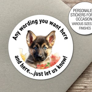 Op de afbeelding: Ronde sticker met een Duitse herder puppy met blauwe ogen en roze bloemen. De sticker zegt "Any wording you want here and here...just let us know!" en "Gepersonaliseerde stickers voor alle gelegenheden. Verschillende maten en afwerkingen."