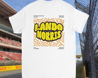 May include: White t-shirt with the words "LANDO NORRIS" in yellow bubble letters on a yellow and orange patterned background. The shirt also includes text that reads "MCLAREN RACING CLUB EST. 1963" and "MIAMI 2024 AFTER PARTY".