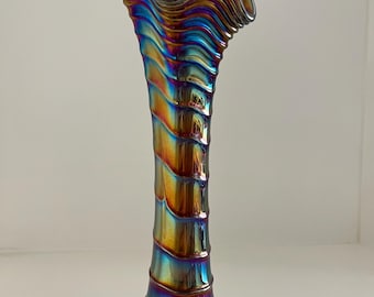 May include: An iridescent glass vase with a ruffled rim and a spiraling, textured body. The vase transitions through a spectrum of colors, including gold, blue, and purple. The base is a darker shade of the same iridescent finish.