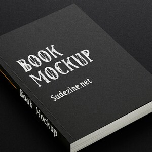 May include: A black book mockup with the text "BOOK MOCKUP" and "Sudezine.net" printed on the cover.