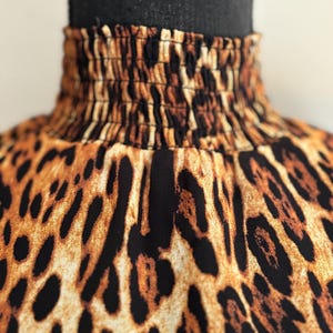 Puede incluir: Primer plano de una tela de estampado de leopardo marr&oacute;n y negro con una banda el&aacute;stica fruncida en la parte superior.